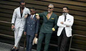 Quattro uomini eleganti in abiti sartoriali. Il completo beige e nero stanno bene insieme, creando un look sofisticato.