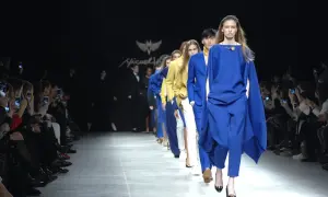 Sfilata di moda con modelli in abbinamento blu elettrico e bianco. Il pubblico scatta foto con i cellulari.