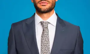 Uomo con abito grigio, camicia bianca e cravatta fantasia. L'abbinamento camicia cravatta è curato nei minimi dettagli.