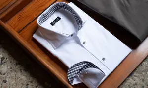 Camicia bianca da uomo con colletto e doppio polsino a quadri marroni e neri, pronta per un'occasione speciale.
