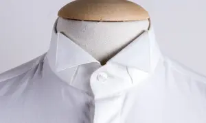 Dettaglio di una camicia bianca da uomo con un elegante camicia con colletto a punta, abbottonata su un manichino.