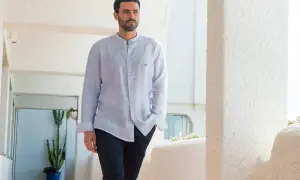 Uomo con camicia a maniche lunghe, dal taglio comodo, con la **lunghezza camicia uomo fuori pantaloni** che crea un look casual.