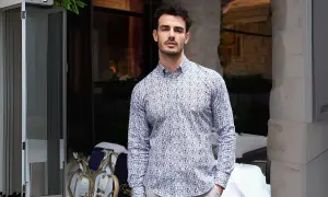 Uomo con camicie di tendenza uomo con fantasia astratta, in piedi all'esterno di un locale.