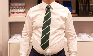 Uomo con camicia bianca e cravatta verde a righe, annodata con un elegante nodo mezzo windsor.