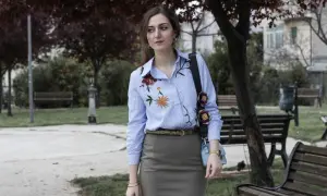 Donna con camicie ricamate a fiori, in un parco con panchine e alberi.