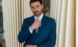 Uomo in abito blu che sistema la cravatta, un esempio di come si mette cravatta con stile.