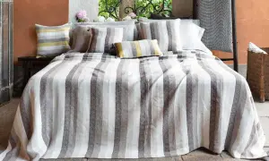 Letto con biancheria a righe grigie e bianche, cuscini coordinati. Un'immagine che ispira su come lavare il lino per mantenerlo morbido.