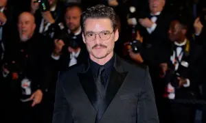 Pedro Pascal sfoggia un impeccabile outfit giacca nera uomo, con camicia e cravatta abbinate, occhiali da vista e baffi.