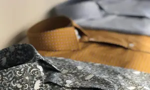 Dettaglio di camicie con fantasie diverse. Una grigia floreale, una senape a pois e una azzurra. Perfette per ogni occasione, con un fermamaniche camicia per un tocco di stile.