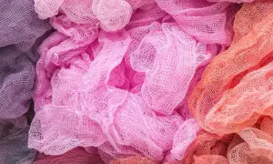 Tessuti morbidi e drappeggiati in tonalità pastello, dal lilla al rosa acceso fino all'arancio. Un'ispirazione per chi vuole imparare come decolorare un tessuto e creare sfumature uniche.