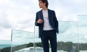 Uomo con completo a quadri blu scuro, maglia bianca. Colori che si abbinano con il blu scuro uomo, su una terrazza con vista mare.