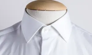Dettaglio di una camicia bianca con collo italiano, pronta per essere indossata.
