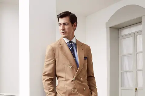 Uomo elegante con abito doppiopetto color cammello e cravatte ultima moda a righe blu.