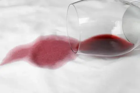 Un bicchiere di vino rosso rovesciato su un tessuto bianco crea macchie che non vanno via con la candeggina.