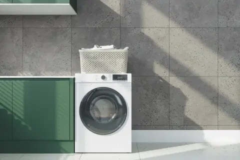 Lavatrice bianca con cestello di biancheria sopra. Impara come lavare pantaloni di lino per mantenerli freschi.