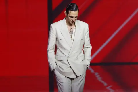 Uomo con completo beige, camicia chiara e collana vistosa. Un perfetto camicia beige abbinamento per un look audace.