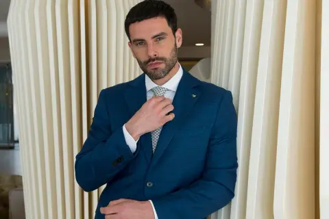 Uomo in abito blu che sistema la cravatta, un esempio di come si mette cravatta con stile.
