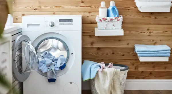 Lavatrice con panni pronti per essere asciugati. Scopri come usare l'asciugatrice per non stirare e avere capi perfetti.