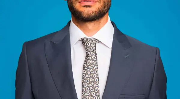 Uomo con abito grigio, camicia bianca e cravatta fantasia. L'abbinamento camicia cravatta è curato nei minimi dettagli.