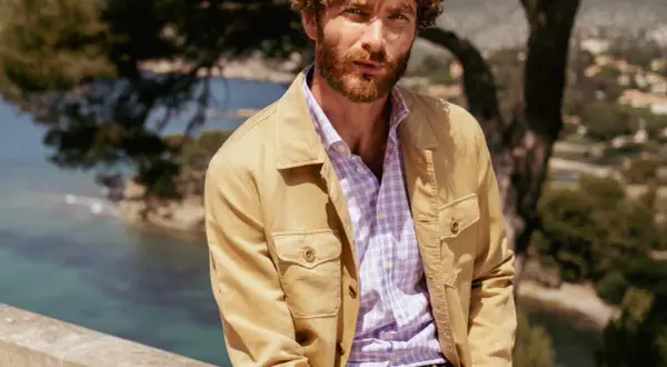 Uomo con camicia a quadri viola e giacca color sabbia, un'idea di cosa mettere sopra una camicia per un look casual chic.