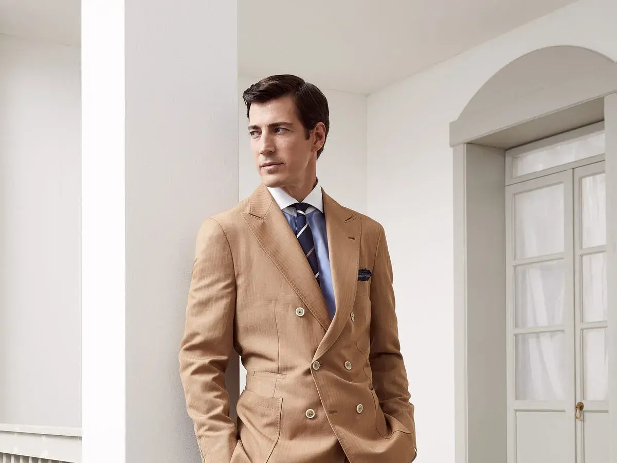 Uomo elegante con abito doppiopetto color cammello e cravatte ultima moda a righe blu.