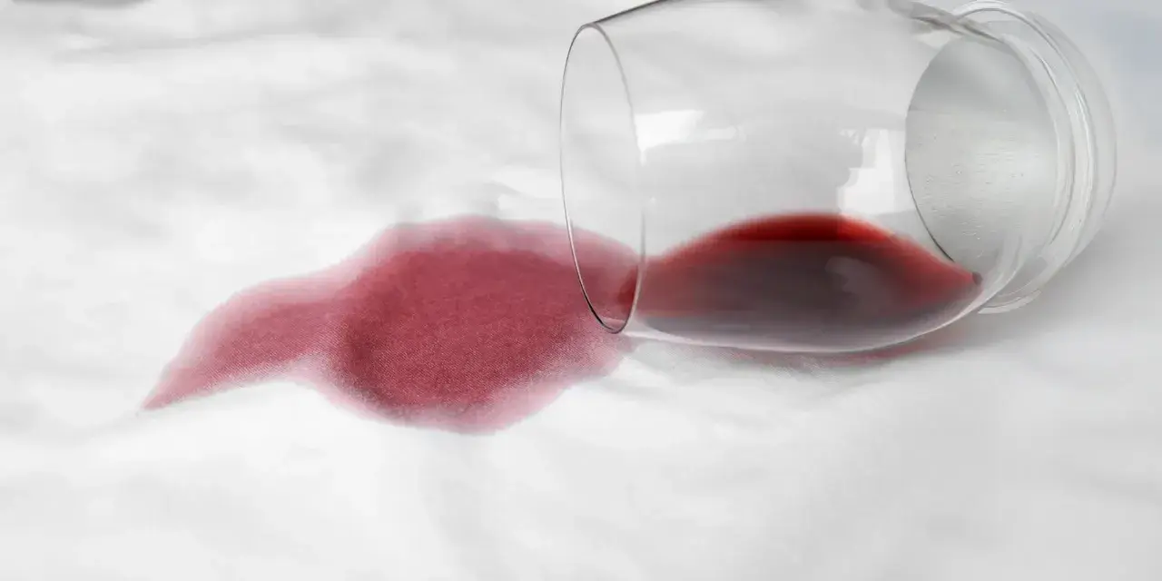 Un bicchiere di vino rosso rovesciato su un tessuto bianco crea macchie che non vanno via con la candeggina.