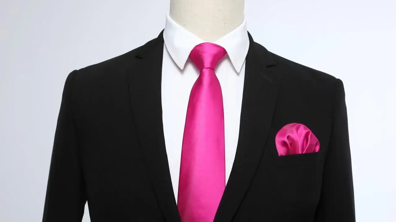 Un completo nero con camicia bianca, una cravatta rosa acceso e un fazzoletto da taschino coordinato. Un abbinamento audace e di classe.