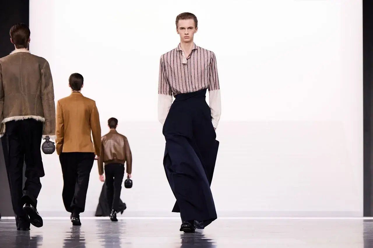 Sfilata di moda maschile: un modello indossa pantaloni ampi blu scuro. Taglia 16 a cosa corrisponde?