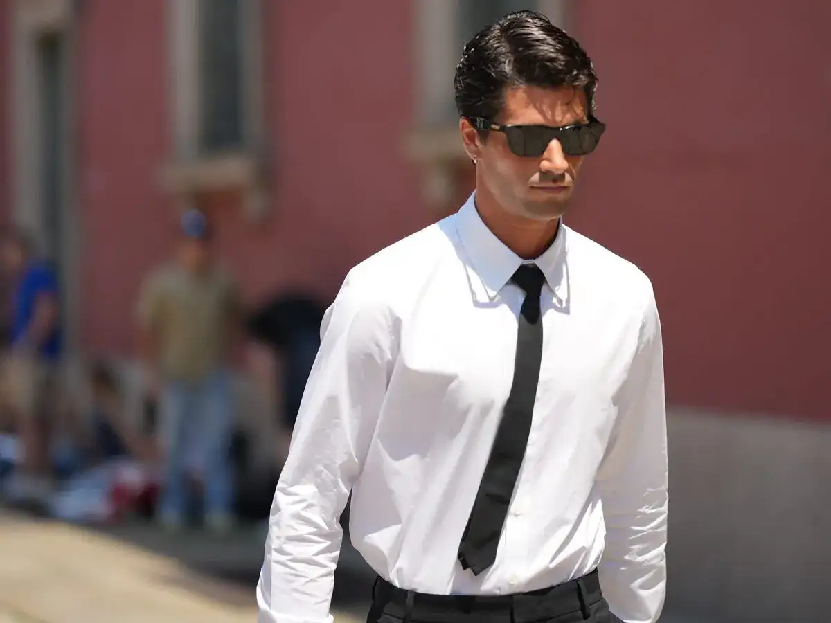 Uomo con camicia bianca e cravatta nera, un esempio di stile con colletti per camicie da uomo impeccabili.