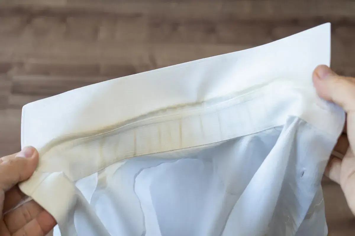 Collo di camicia bianca ingiallito, pronto per essere lavato a mano per rimuovere le macchie.