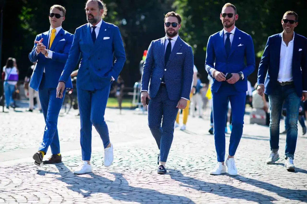 Uomini eleganti in abiti blu, con dettagli che creano un look moderno. I colori che si abbinano con il blu scuro uomo sono vari, qui vediamo il giallo e il bianco.