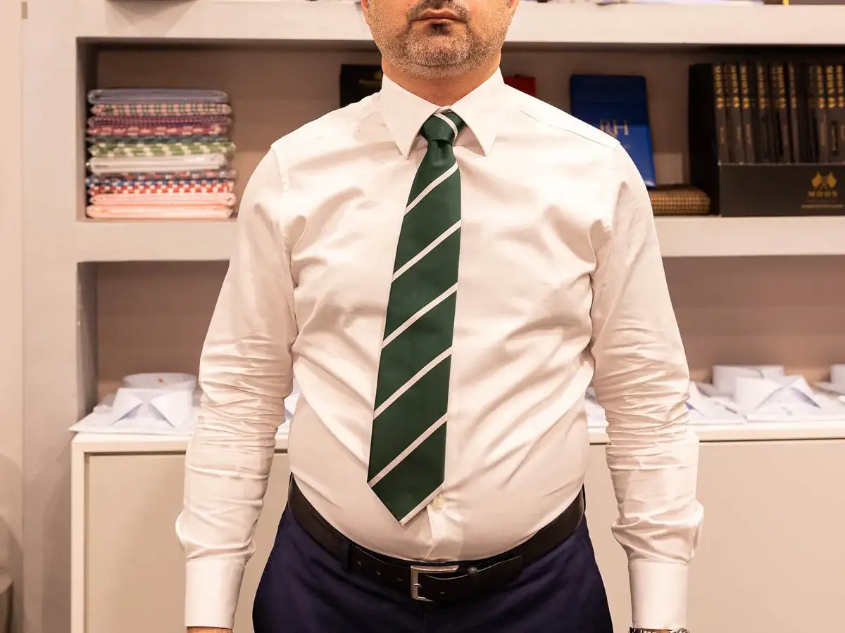 Uomo con camicia bianca e cravatta verde a righe bianche, un perfetto nodo cravatta simmetrico.