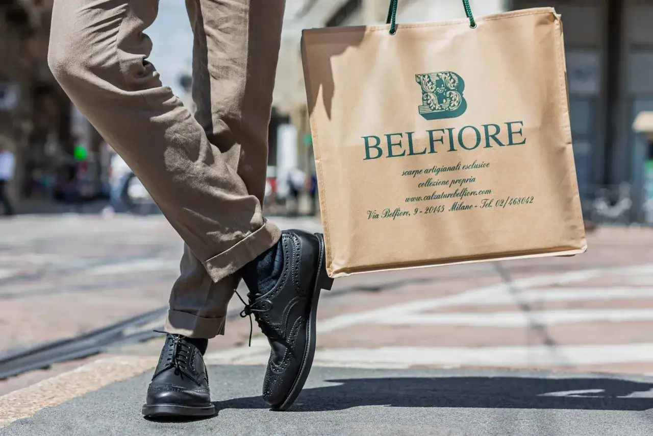 Uomo con pantaloni beige e scarpe stringate nere, porta una borsa Belfiore. Perfetti abbinamenti vestiti uomo per un look elegante.