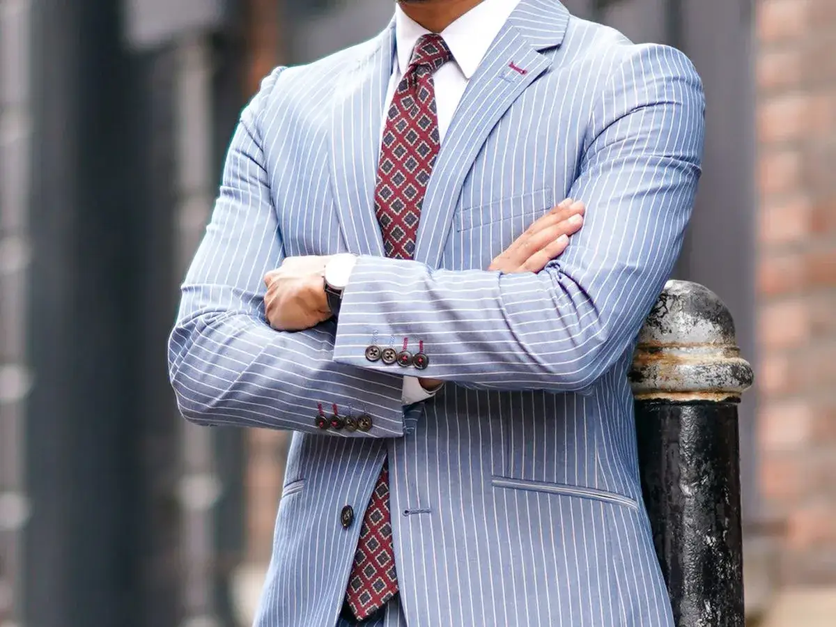 Uomo con completo gessato azzurro e cravatte ultima moda con fantasia geometrica.