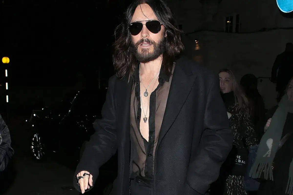 Jared Leto con camicia trasparente e cappotto nero. Sotto la camicia, un top nero o una canotta sono un'ottima opzione per cosa mettere sotto una camicia trasparente.