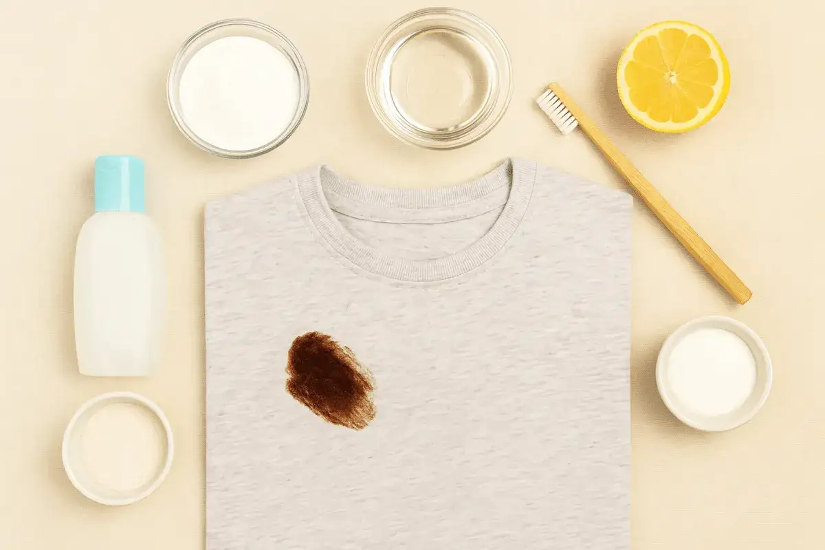 T-shirt con macchia di cioccolato e ingredienti per rimuoverla: bicarbonato, limone, spazzolino. Ecco come togliere le macchie di cioccolato!