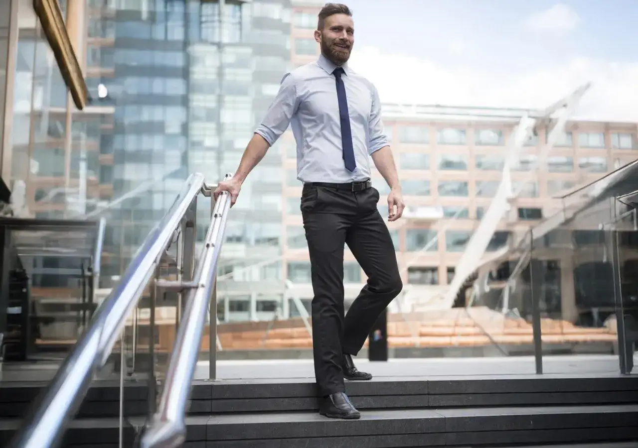 Uomo con pantaloni neri, camicia azzurra e cravatta blu, un look da ufficio impeccabile.