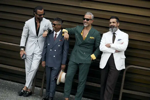 Quattro uomini eleganti in abiti sartoriali. Il completo beige e nero stanno bene insieme, creando un look sofisticato.