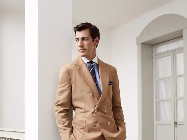 Uomo elegante con abito doppiopetto color cammello e cravatte ultima moda a righe blu.