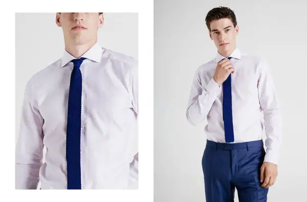 Uomo con camicia per cravatta rosa pallido e cravatta blu a maglia. Pantaloni blu eleganti.
