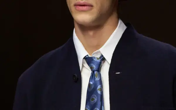 Primo piano di un uomo con un elegante nodo cravatta matrimonio, indossa una camicia bianca e una giacca blu scuro.