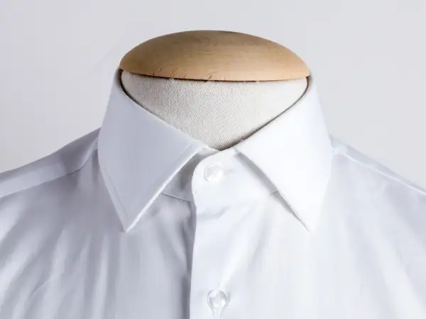 Dettaglio di una camicia bianca con collo italiano, pronta per essere indossata.