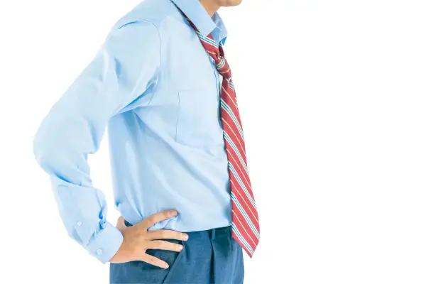 Uomo con camicia azzurra e cravatta a righe rosse, gialle e bianche. La lunghezza cravatta è visibile, arrivando appena sotto la cintura.