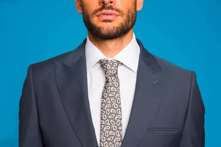 Uomo con abito grigio, camicia bianca e cravatta fantasia. L'abbinamento camicia cravatta è curato nei minimi dettagli.